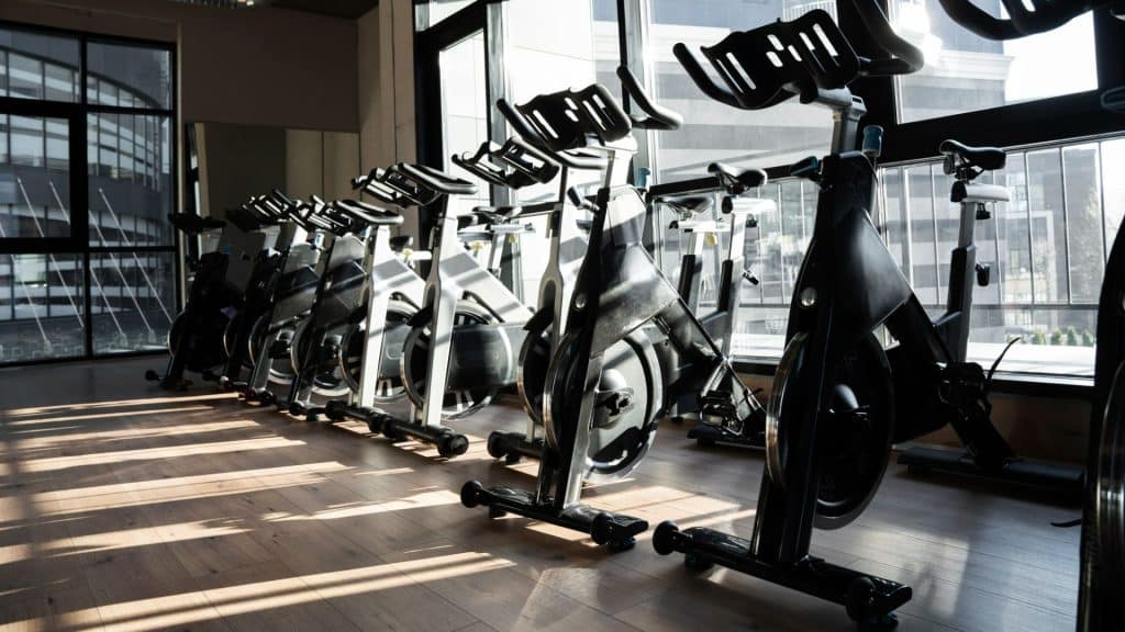 Homme courant sur un tapis roulant dans une salle de sport et regardant par la fenêtre