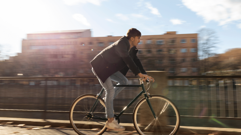 Un joven vestido con ropa informal monta en bicicleta al aire libre en un día soleado, representando el vínculo entre el ciclismo y la fertilidad masculina.