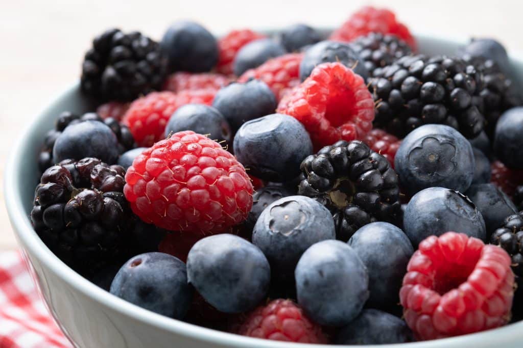 Primer plano de arándanos, frambuesas y moras en un cuenco, ricos en antioxidantes que favorecen la salud del esperma.